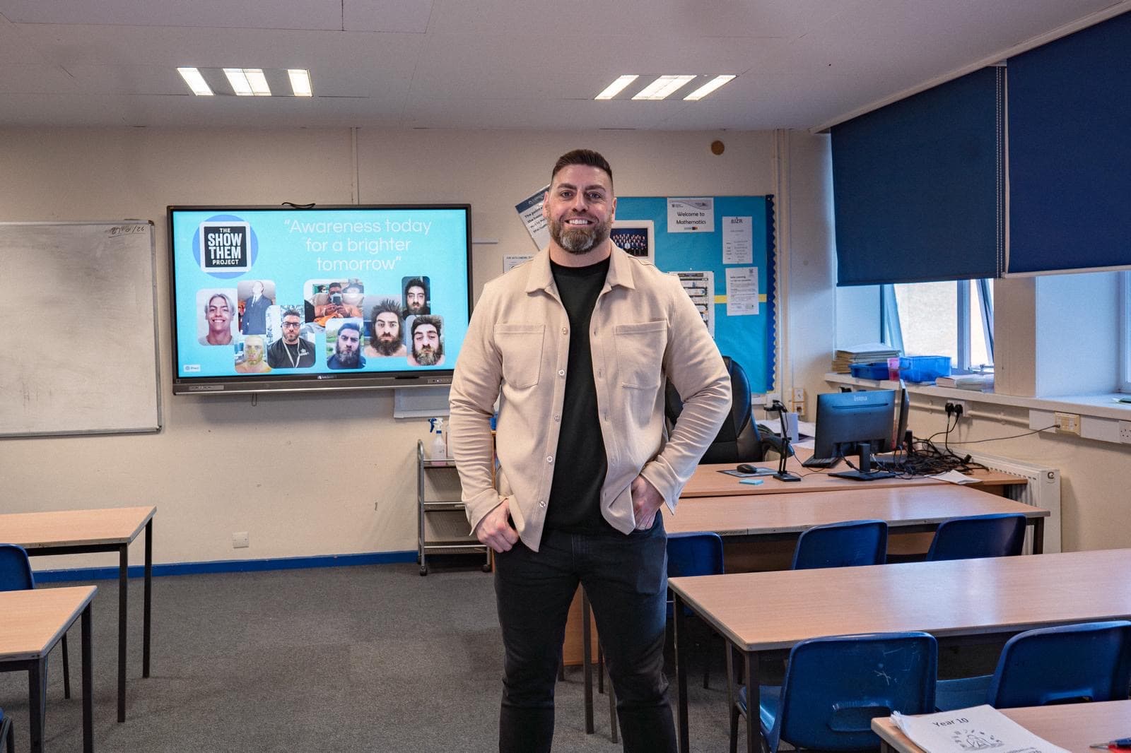 Mark Bragg standing in a classroom with The Show Them Project presentation